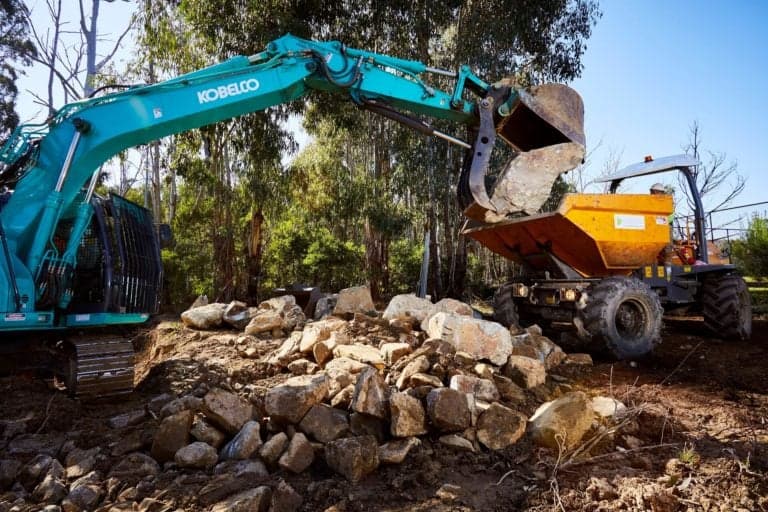 Excavator loading rocks into a dump truck