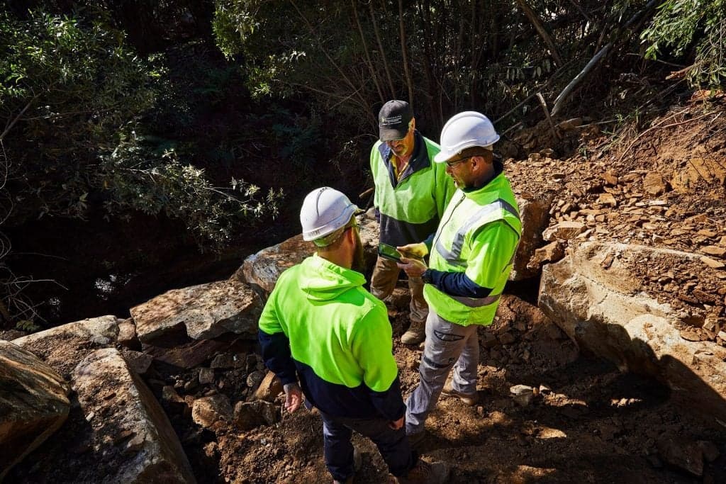 Construction workers discuss plans outdoors.