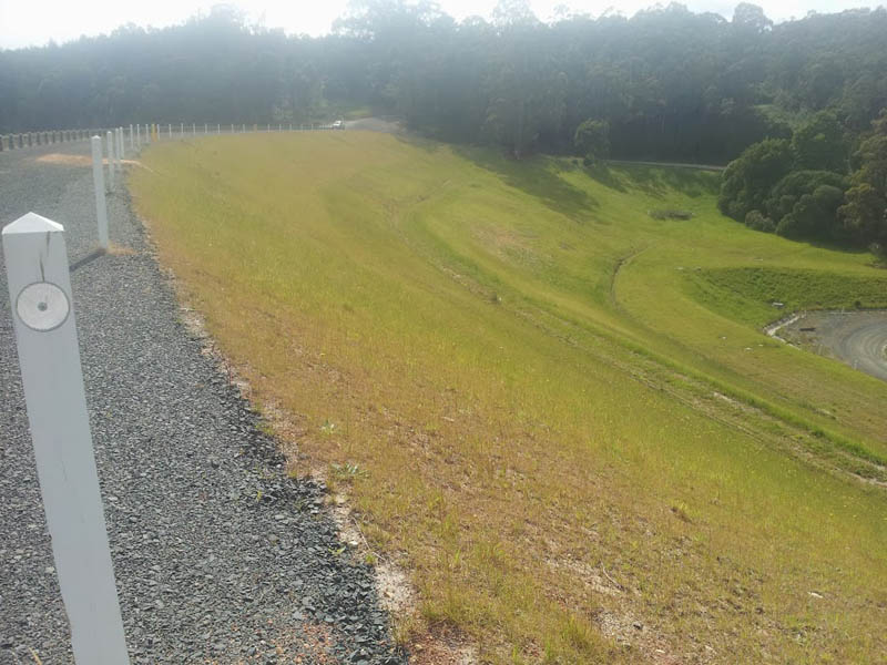 Grassy dam slope with fence