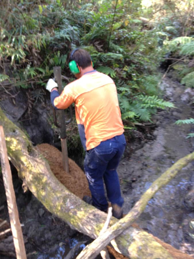 Worker using jackhammer on log