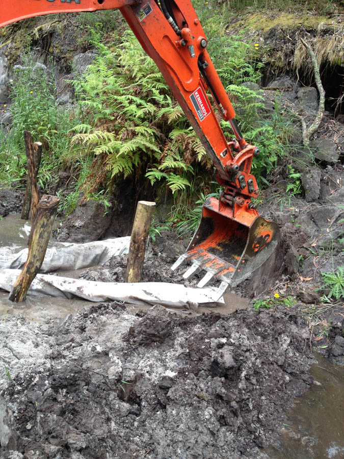 Excavator digging muddy ground