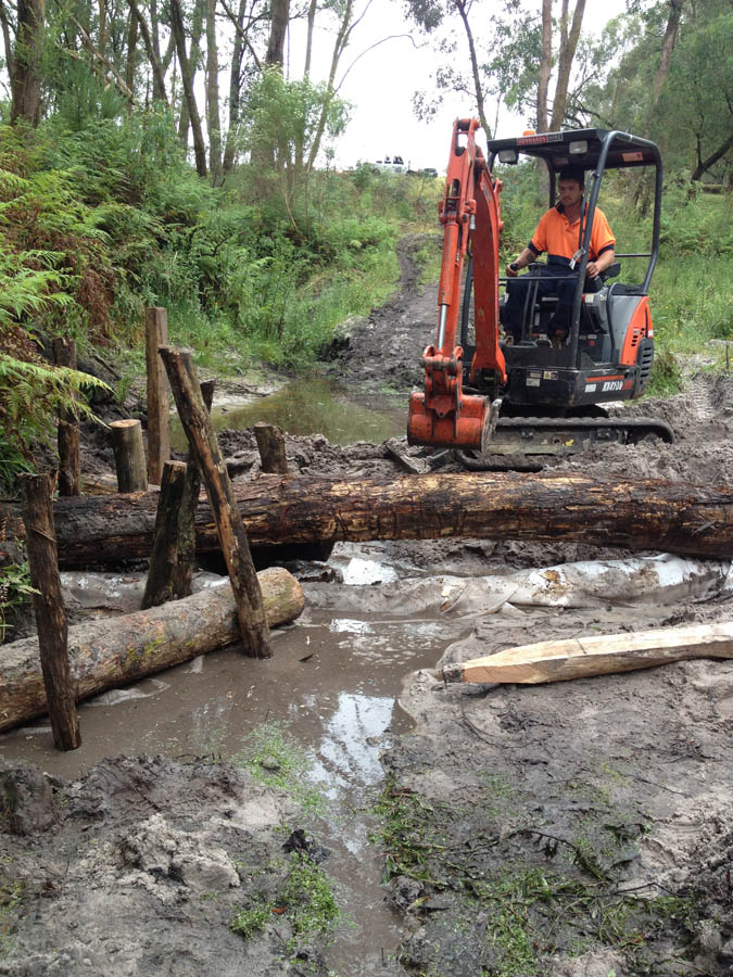 Mini excavator clearing logs