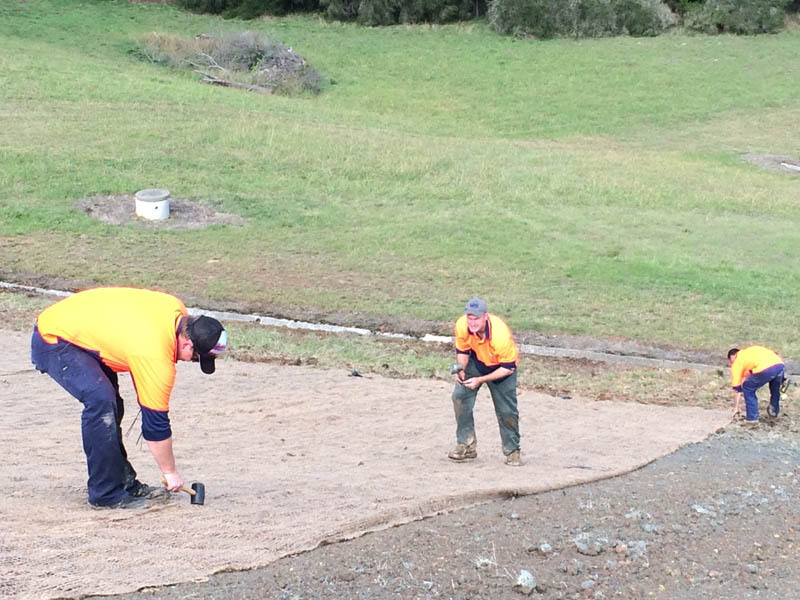 Workers lay erosion control mat