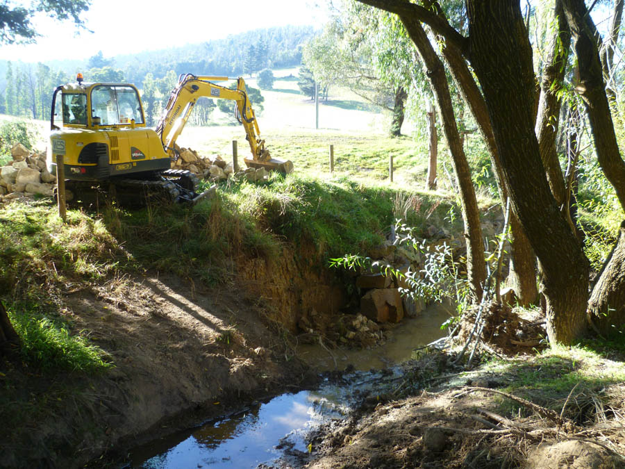 Yellow excavator digging ditch