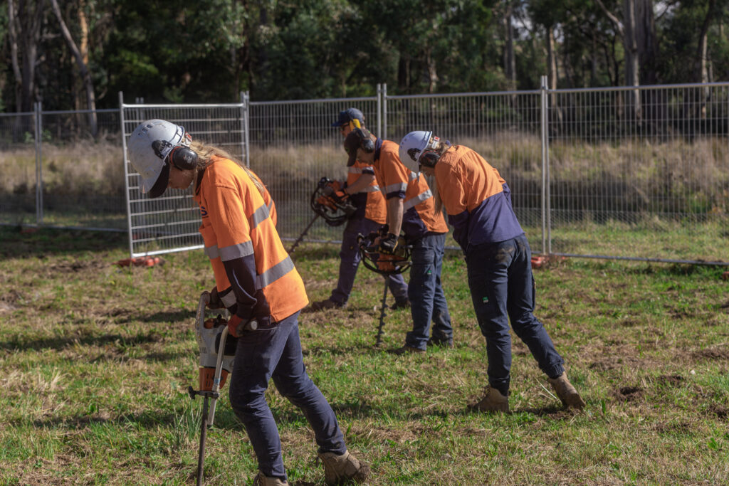 Workers operate equipment outdoors.