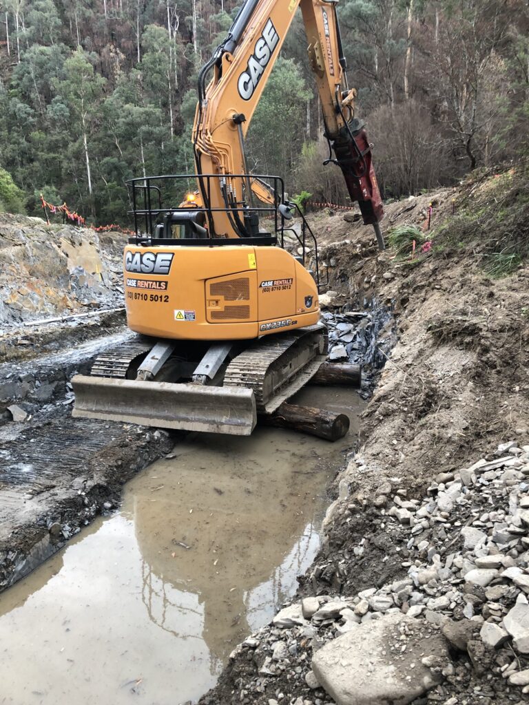 Excavator breaking rock in water