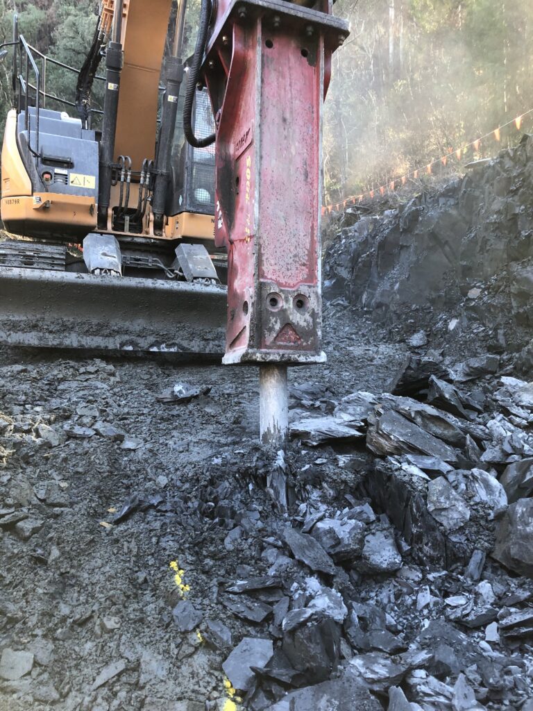 Excavator breaking rocks